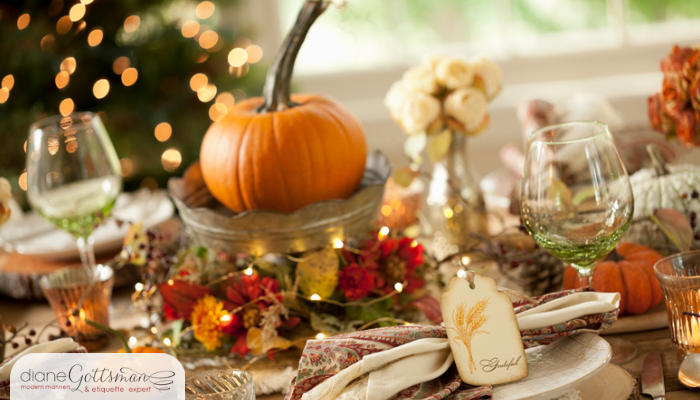 Thanksgiving Host Etiquette | table set for Thanksgiving with pumpkins, flowers, and lights