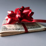 2024 Holiday Tipping Guide | Holiday Tipping Etiquette 2024 | Roll of cash with red bow