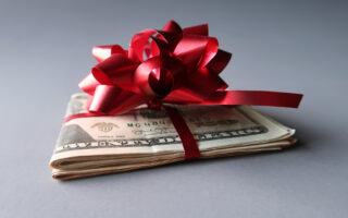 2024 Holiday Tipping Guide | Holiday Tipping Etiquette 2024 | Roll of cash with red bow