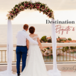 Destination Wedding Etiquette & FAQs | Couple at beach wedding looking out over the water through a flower arch