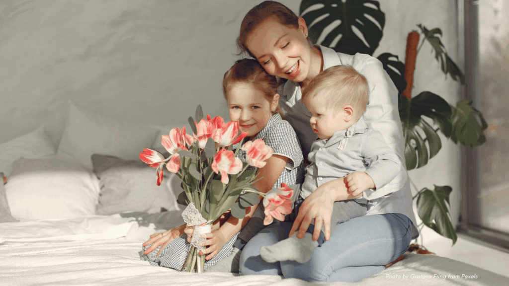 Mother and two young children in gray colors, with beautiful coral and white flowers
