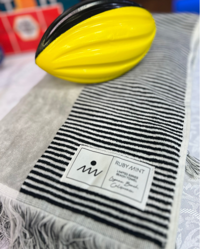 Ruby Mint and Diane Gottsman | Luxury Beach Towel in black and white, with yellow foam football in the shot
