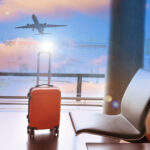 Fall Girls Trip Etiquette | Travel concept with orange luggage in the airport terminal waiting area, summer vacation concept, traveling and enjoying concept