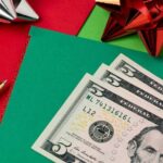 Holiday tipping guide 2025 and etiquette reminders - Crisp $5 bills on top of bright green and red holiday envelopes
