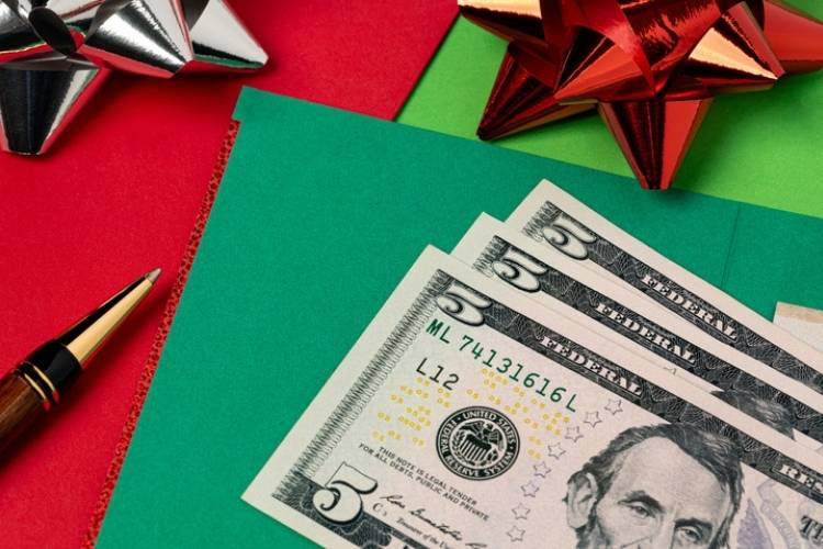 Holiday tipping guide 2025 and etiquette reminders - Crisp $5 bills on top of bright green and red holiday envelopes