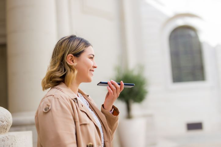 Happy woman dictating message on phone