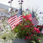 Fourth of July party etiquette | American flags interspersed among summer flowers in Chatham, Massachusetts, United States