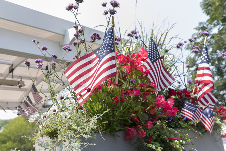 Fourth of July party etiquette | American flags interspersed among summer flowers in Chatham, Massachusetts, United States