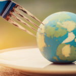 International Tipping Etiquette: Restaurant Customs in Popular Travel Destinations | Fork slammed on Globe model placed on plate for serve menu in famous hotel. International cuisine is practiced around the world often associated with specific region country. World food inter concept