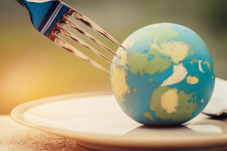International Tipping Etiquette: Restaurant Customs in Popular Travel Destinations | Fork slammed on Globe model placed on plate for serve menu in famous hotel. International cuisine is practiced around the world often associated with specific region country. World food inter concept