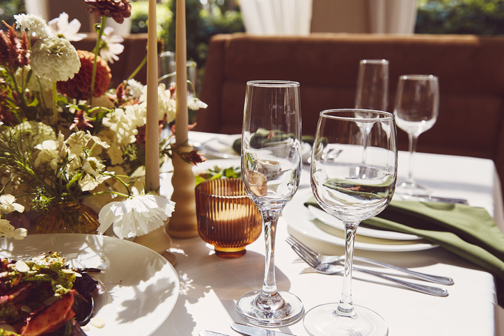 fall glassware and dining etiquette | Sophisticated tableau arrangement on the table, adorned with candles and flowers beneath the play of shadows. A wedding style reminiscent of Provence aesthetics